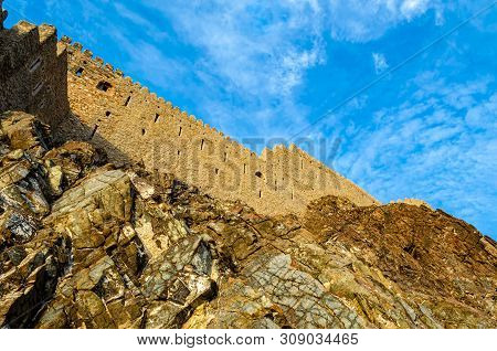 Muttrah Fort Wall On The Rocky Hill With Blue Sky Background. Shot From Below In Muscat,oman.
