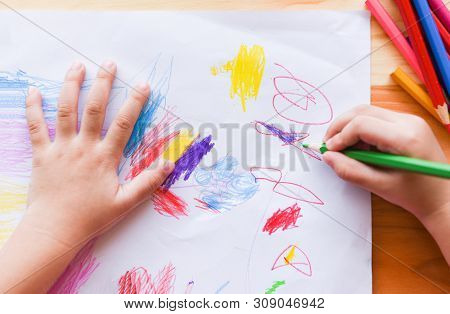 Girl Painting On Paper Sheet With Colour Pencils On The Wooden Table At Home / Child Kid Doing Drawi