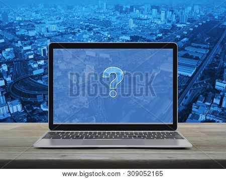 Question Mark Sign Icon With Modern Laptop Computer On Wooden Table Over City Tower, Street, Express