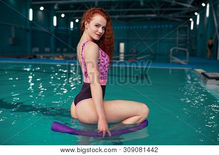 A Beautiful Young Red-haired Girl In A Fashionable Swimsuit In The Style Of The 80s Stands With A No