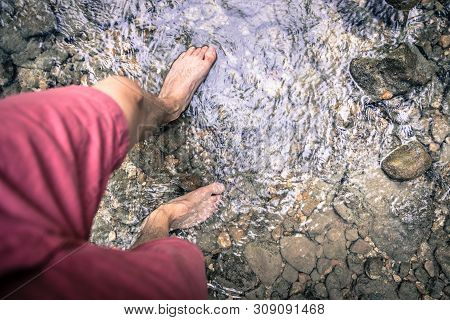 Hiking Outdoors In The Forest: Cut Out Of Male Barefoot Feet In A Shallow River, Fresh Water