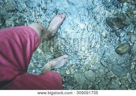 Hiking Outdoors In The Forest: Cut Out Of Male Barefoot Feet In A Shallow River, Fresh Water