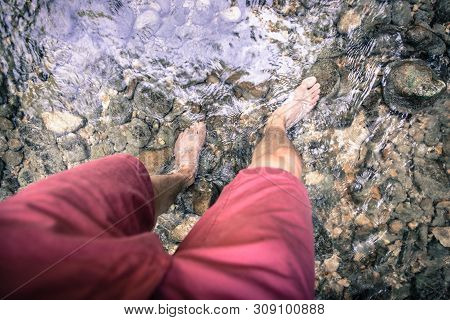 Hiking Outdoors In The Forest: Cut Out Of Male Barefoot Feet In A Shallow River, Fresh Water