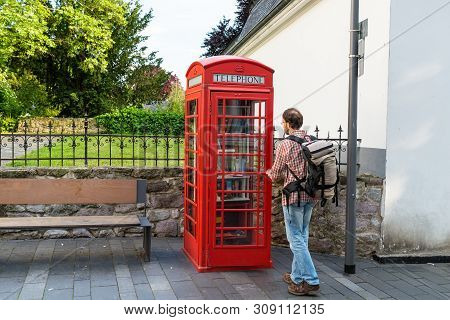 Konigswinter, Germany - 23 May 2019. A Red Telephone Booth For The Free Exchange Of Books. A Man Loo