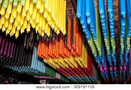 Long Rows Of Candles Of Different Colors Hanging From Rack In Production.
