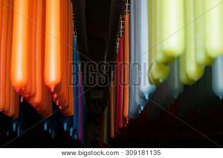 Long Rows Of Candles Of Different Colors Hanging From Rack In Production.