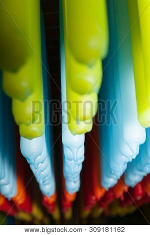 Long Rows Of Candles Of Different Colors Hanging From Rack In Production.