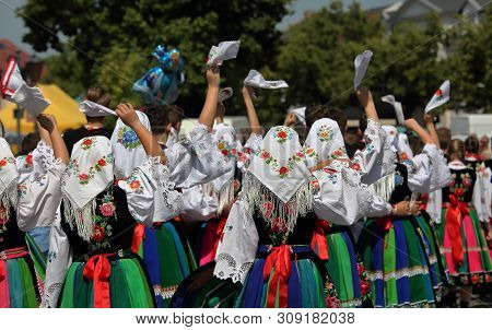Crowd Of Girls In Traditional Colorful Folk Costumes From Lowicz  Region On Street, Waving Handkerch