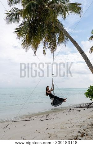 A Young Girl Riding On A Swing. Swing Suspended On The Palpe Above The Water