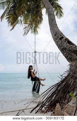A Young Girl Riding On A Swing. Swing Suspended On The Palpe Above The Water