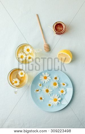 Chamomile Flowers And Chamomile Tea. Chamomile Tea In Glass Teacup With Flowers, Honey And Lemon, To