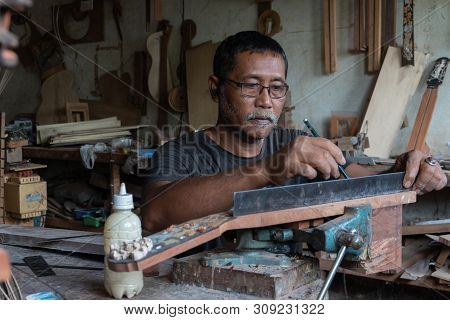 Gianyar,bali/indonesia-may 30 2019: A Guitar Craftsman Is Measuring And Make Sure It Is A Precision