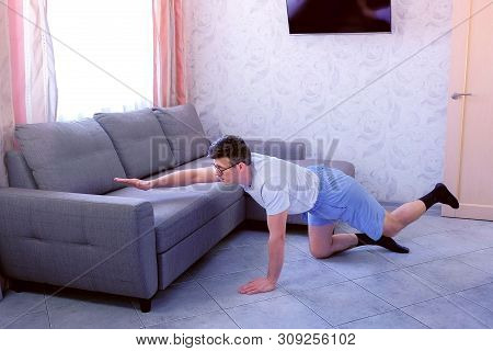 Funny Nerd Man In Glasses And Shorts Is Doing Balance Pose On All Fours At Home. Sport Humor Concept