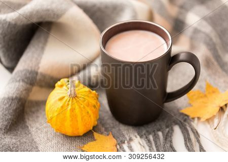 drinks and season concept - cup of hot chocolate, autumn leaves, pumpkin and warm blanket on white background
