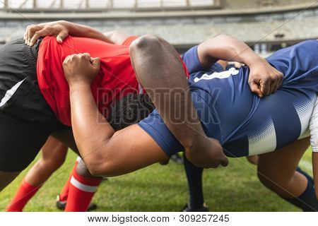 Side view close up of diverse male rugby players playing rugby match in stadium. 