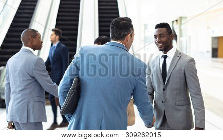 Side view of diverse young executives meeting in front of escalator in modern office