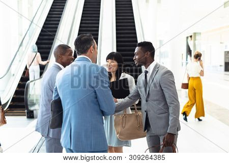 Side view of diverse young executives meeting in front of escalator in modern office