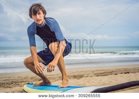 Man Surfer On The Beach Warming Up Before Surfing, Surf Man In A Wet Suit With A Surfboard On The Oc