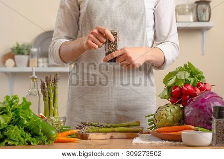 Close-up, Chef Peppers Asparagus, With Vegetables On A Light Background. A Concept Of Losing Healthy