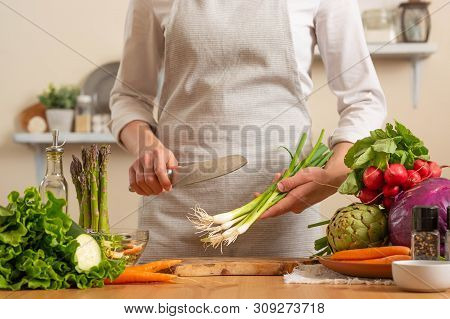 Chef Cook With Green Onions, On A Light Background. The Concept Of Losing Healthy And Wholesome Food