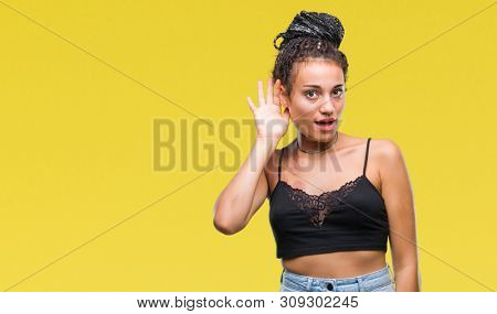 Young braided hair african american with pigmentation blemish birth mark over isolated background smiling with hand over ear listening an hearing to rumor or gossip. Deafness concept.