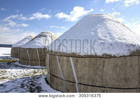 Yurts Under The Snow In The Middle Of A Snow-covered Field Against A Sky With Clouds. Travel Kyrgyzs