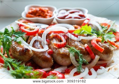 Fried Pork Sausages On Pita Bread With Ketchup And Armenian Appetizer Aivar With Vegetables. Lavash,