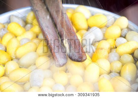 Closed Up Of Vintage Method For Silk Reeling And Yellow And White Cocoon On Hot Water Background