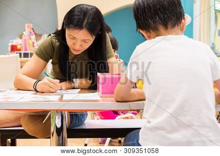 Kids Are Painting Picture With Color Pencil With Their Teacher In The Classroom To Learn Paint Skill