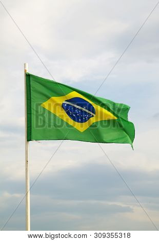 Brazilian Flag On A Blue Sky With Clouds Background