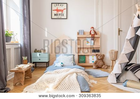 Cozy Kids Bedroom With Blue Bedding And Warm Blanket On The Bed, Real Photo With Mockup Poster On Th