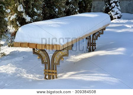 Bench In Winter Covered With Heavy Snow.