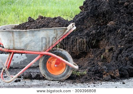 Old Wheelbarrow With Ground Near The Heap Of Soil. Earthworks, Urban Landscaping, Laying Of Undergro