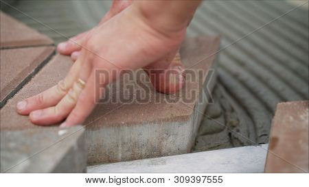 Worker Lay Tiles On The Sidewalk. Laying Concrete Paving Slabs In House Courtyard Driveway Patio. Pr