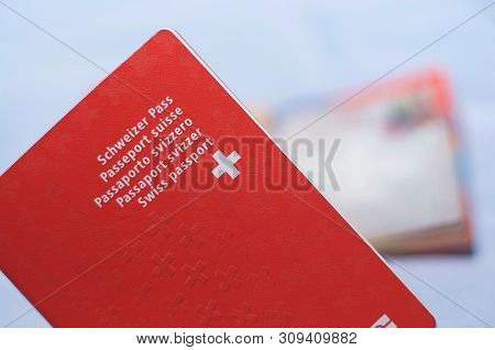 Close Up View Of One Swiss Passports With A Blurred Open Swiss Passport On The Background