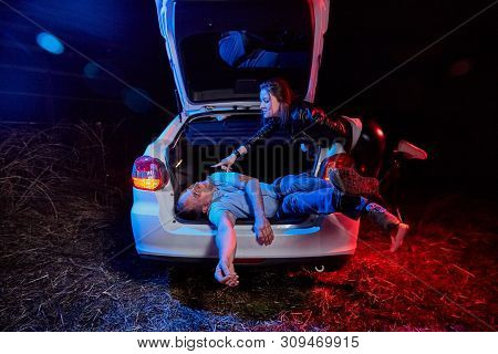 Female Bandit Near The Car And A Dead Or Drunk Guy In The Trunk At Night. Photoshoot About Life Of G