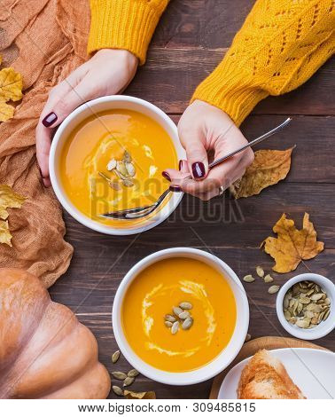 Womans Hands Holding Table Sppoon Near The Bowl Of Delecious Homemade Pumpkin Soup With Cream On The