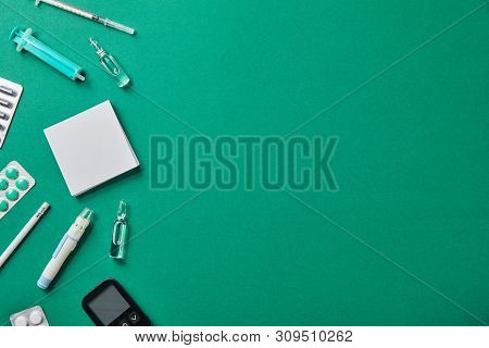 Blister Packs, Ampules, Blood Lancet, Glucometer, Syringes, Sticky Notes And Pencil On Green Backgro