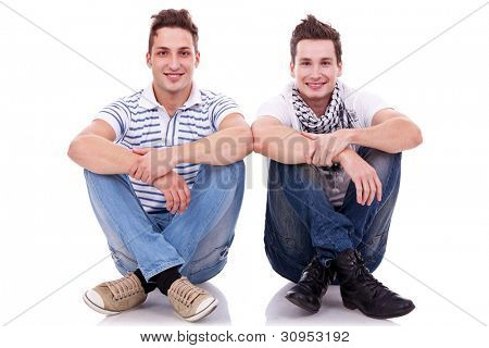 two men friends looking very happy, sitting next to each other on white background
