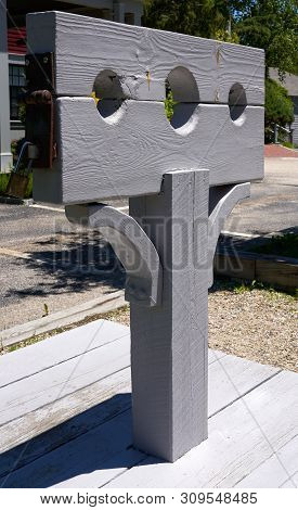 Grey Wooden Post With Pillory Or Stocks Used For Restraint Of A Person For Punishment And Public Hum