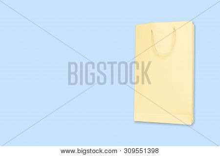 Light Yellow Color Shopping Paper Bag On Blue Background With Copy Space.