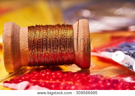 Embroidery Products And Tools. The Spool Of Metallic Thread, Japanese Seed Beads And Sequins On A Ye