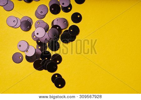 Embroidery Products And Tools. Black Sequins On Yellow Background.