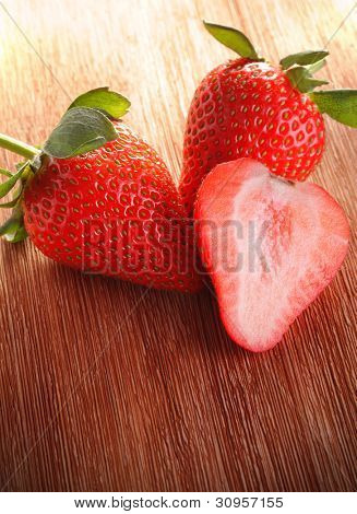 trois fraises sur terrasse en bois