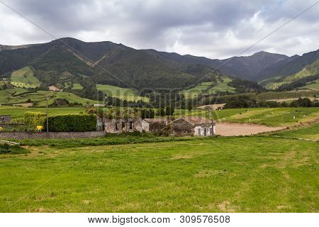 Green And Fresh Country Surrounding A Village Lomba Do Pomar. Fields And A Farm. Mountains In The Ba