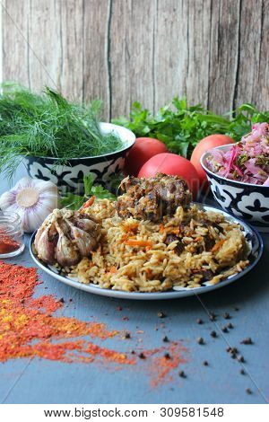 Pilaf On A Platter Of Meat And Spices.pilaf In A Plate On A Wooden Background, Top View.  The Concep