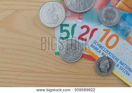 Close Up Picture Of Swiss Banknotes And Coins On A Wooden Table