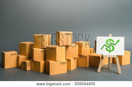 Plenty Of Cardboard Boxes And Sign With A Dollar Symbol Green Up Arrow. Rate Growth Of Production Of
