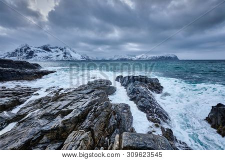 Waves of Norwegian sea crushing at rocky coast in fjord. Vikten, Lofoten islands, Norway