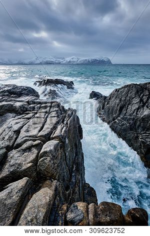 Waves of Norwegian sea crushing at rocky coast in fjord. Vikten, Lofoten islands, Norway